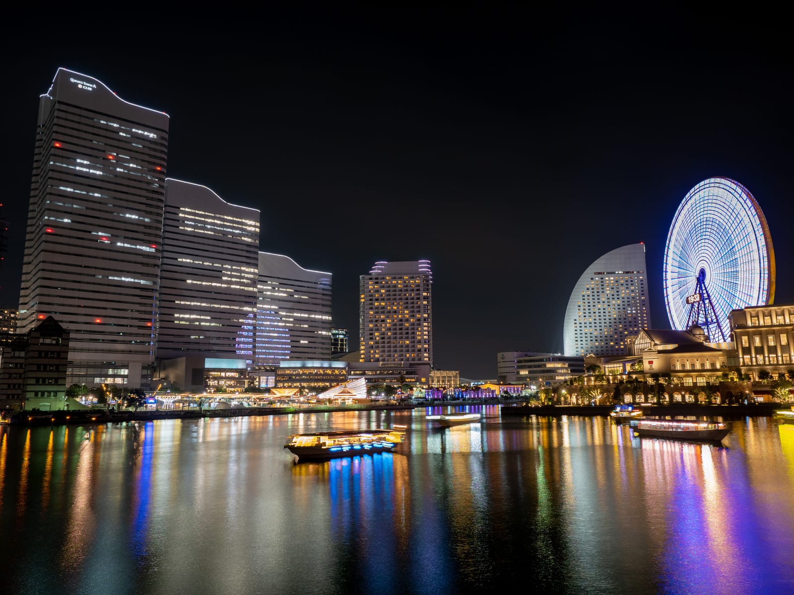 The Minato Mirai skyline and Cosmo Clock Ferris wheel at night, reflected in the harbor